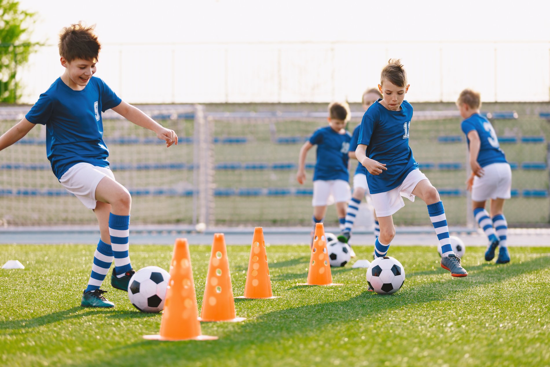 Children Practicing to Play Football in Field